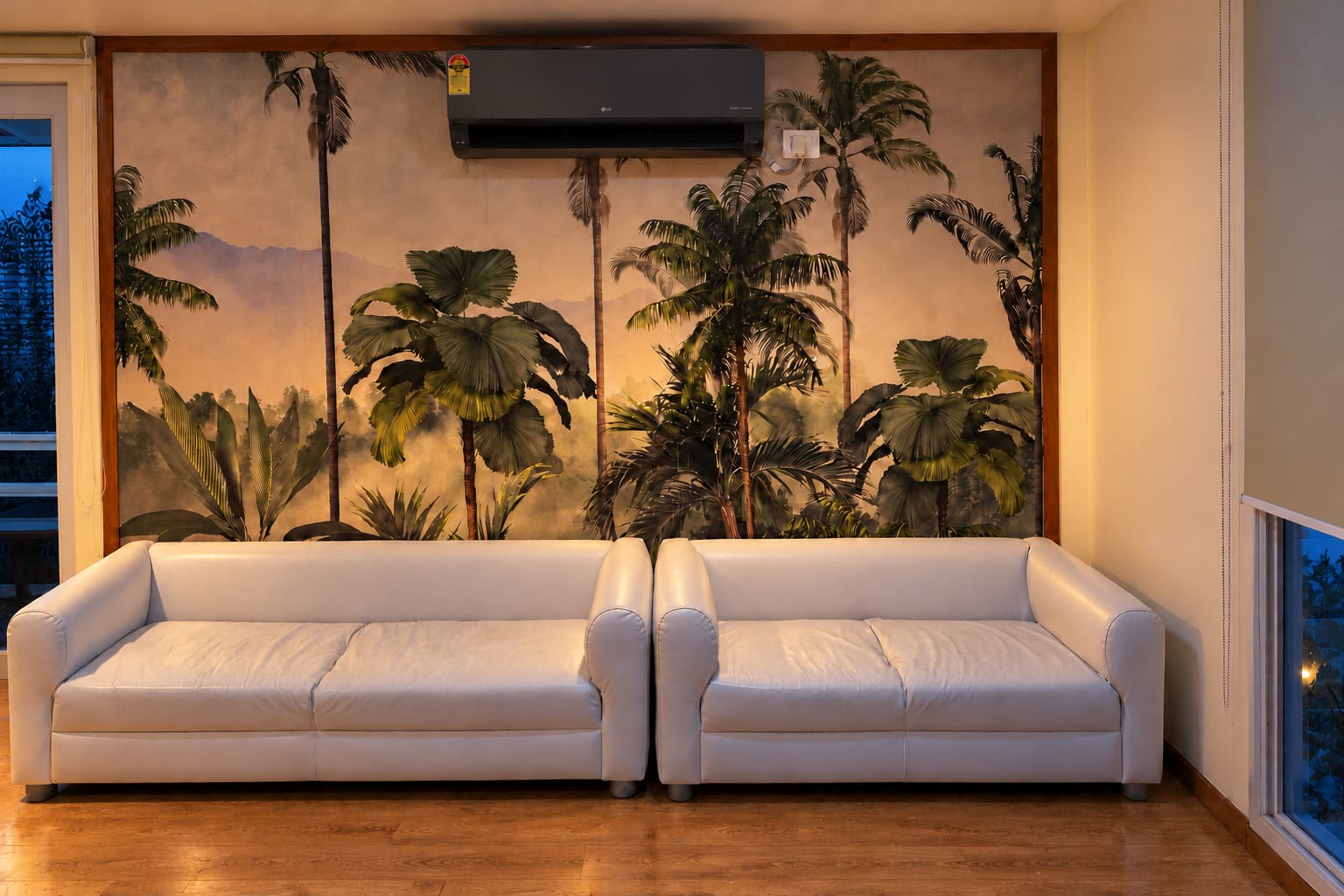 Two white sofas below a palm-tree mural in the homestay lounge